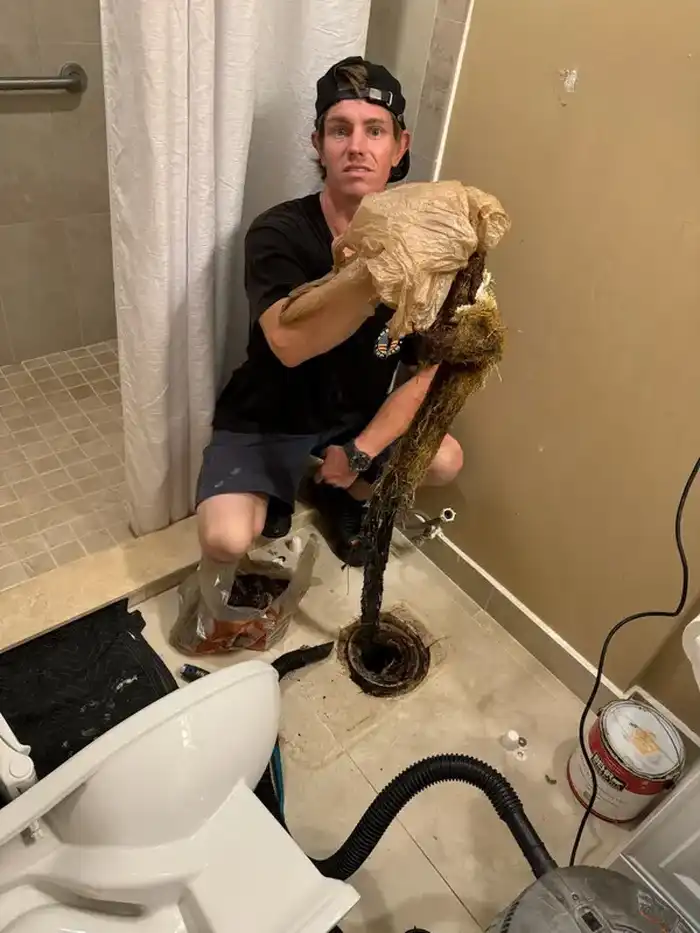 Technician removing tree roots pulled from a main sewer line